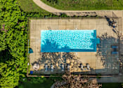 Thumbnail 22 of 25 - An aerial view of a rectangular swimming pool surrounded by a concrete patio and a grassy area.