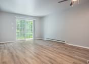 Thumbnail 8 of 25 - A room with wooden flooring and a sliding glass door leading to a balcony.