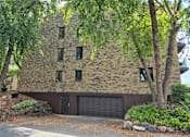 Thumbnail 19 of 25 - A house with a black garage door is surrounded by trees.