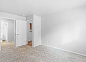 Thumbnail 10 of 25 - A white room with a carpeted floor and two open doors.
