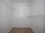 Thumbnail 14 of 16 - a walk in closet in a bedroom with white walls and carpet