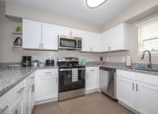 Thumbnail 4 of 16 - newly renovated kitchen with white cabinets, stainless steel appliances, and granite countertops