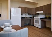 Thumbnail 3 of 21 - A kitchen with a white refrigerator and a dining table with two bowls on it.