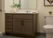 Thumbnail 12 of 21 - A bathroom with a toilet, sink, and mirror.