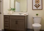 Thumbnail 15 of 21 - A bathroom with a toilet, sink, and mirror.