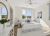Thumbnail 11 of 21 - A bedroom with a large bed, a ceiling fan, and a view of trees outside the window.