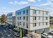 Thumbnail 1 of 21 - A modern building with a parking lot in front.