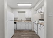 Thumbnail 5 of 38 - White kitchen with electric stove and skylight at Parks on the Green Apartments, Temple, TX