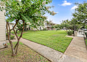 Thumbnail 15 of 38 - Manicured lawn with walkway and pool gate at Parks on the Green Apartments, Temple, 76504
