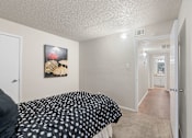 Thumbnail 30 of 38 - Bedroom with hallway view and umbrella artwork at Parks on the Green Apartments, Temple, TX