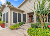 Thumbnail 26 of 38 - Front entrance with landscaped beds and accent door at Parks on the Green Apartments, Temple, TX