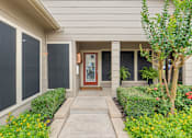 Thumbnail 25 of 38 - Covered front entry with potted ferns and landscaping at Parks on the Green Apartments, Temple, 76504