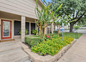 Thumbnail 17 of 38 - Building entrance with landscaped garden and flowers at Parks on the Green Apartments, Temple, Texas