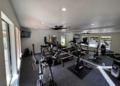 Thumbnail 22 of 22 - A gym with a row of exercise bikes and a television.
