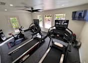 Thumbnail 21 of 22 - A room with a treadmill and a fan.