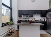 Thumbnail 10 of 14 - A kitchen with a black counter top and stainless steel appliances.