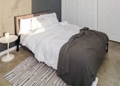Thumbnail 4 of 14 - A bedroom with a bed, a nightstand, and a ceiling fan.