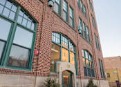 Thumbnail 3 of 14 - A red brick building with green trim and windows.