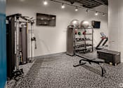 Thumbnail 13 of 18 - A gym with a weight rack, a bench, and a row of dumbbells.