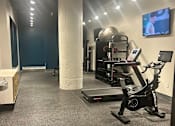 Thumbnail 18 of 18 - A gym with a treadmill, a rowing machine and a television.