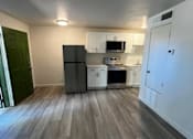 Thumbnail 4 of 8 - A kitchen with a black fridge and white cabinets.