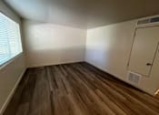 Thumbnail 1 of 8 - A room with wooden flooring and a window with blinds.