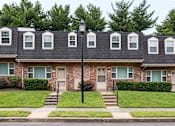 Thumbnail 1 of 22 - A row of houses with green bushes in front.