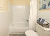 Thumbnail 16 of 26 - A white bathroom with a tub, toilet and sink.