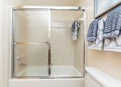 Thumbnail 24 of 31 - A small white bathroom with a glass shower door.