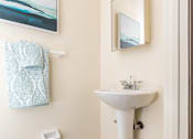 Thumbnail 14 of 31 - A bathroom with a white sink and a blue rug.
