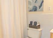 Thumbnail 15 of 26 - A white toilet in a bathroom with a shower curtain.