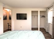 Thumbnail 8 of 15 - A bedroom with a bed, a TV, and a window with curtains at Kingston Townhomes, Baltimore, MD