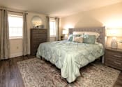 Thumbnail 7 of 15 - A bedroom with a bed, nightstand, and window at Kingston Townhomes, Baltimore, MD