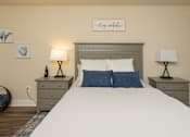 Thumbnail 15 of 27 - A bedroom with a bed, two lamps, and a wall art.at Deer Park Apartments, Randallstown, 21133