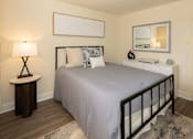 Thumbnail 7 of 10 - A bedroom with a bed, nightstand, and lamp at Hyde Park Apartments*, Essex, MD 21221