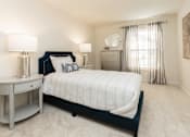 Thumbnail 19 of 31 - A bedroom with a large bed, a nightstand, and a dresser.