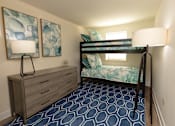 Thumbnail 9 of 15 - A room with a bunk bed, a dresser, and a patterned carpet at Kingston Townhomes, Baltimore, MD