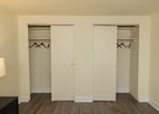 Thumbnail 21 of 26 - Two white closet doors with clothes hanging on them.