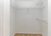 Thumbnail 17 of 31 - Empty walk-in closet with white walls and shelving.