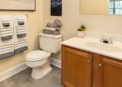 Thumbnail 7 of 29 - Guest bathroom with a toilet sink, and mirror at Woodridge Apartments in Randallstown, MD 21133.