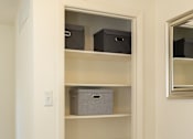 Thumbnail 34 of 36 - A white shelving unit with three shelves and two storage boxes on the bottom shelf.