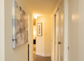 Thumbnail 13 of 26 - A hallway with a rug on the floor and a painting on the wall.