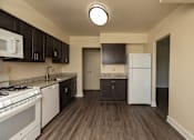Thumbnail 9 of 16 - A kitchen with white appliances and dark brown cabinets at Lawyers Hill Apartments, Elkridge, 21075