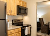 Thumbnail 2 of 28 - A kitchen with wooden cabinets and a black refrigerator.