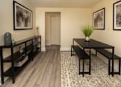 Thumbnail 9 of 26 - A black table with a plant on it sits in the middle of a room with a wooden floor and a carpet.