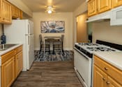 Thumbnail 8 of 27 - A kitchen with wooden cabinets and a white stove top oven.at Deer Park Apartments, Maryland, 21133
