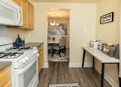 Thumbnail 4 of 20 - A kitchen with a white stove and a white microwave above it. at Colony Hill Apartments & Townhomes, Baltimore, Maryland