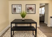 Thumbnail 8 of 26 - A black table with a plant on it and two framed pictures on the wall.