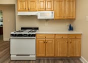 Thumbnail 5 of 27 - A kitchen with wooden cabinets and a white stove.at Deer Park Apartments, Maryland