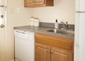 Thumbnail 6 of 36 - A white dishwasher is in a kitchen with wooden cabinets